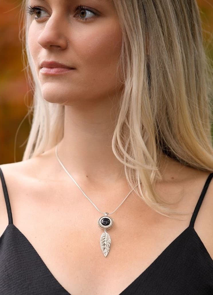 Falling Leaf necklace with black onyx, worn against autumn foliage